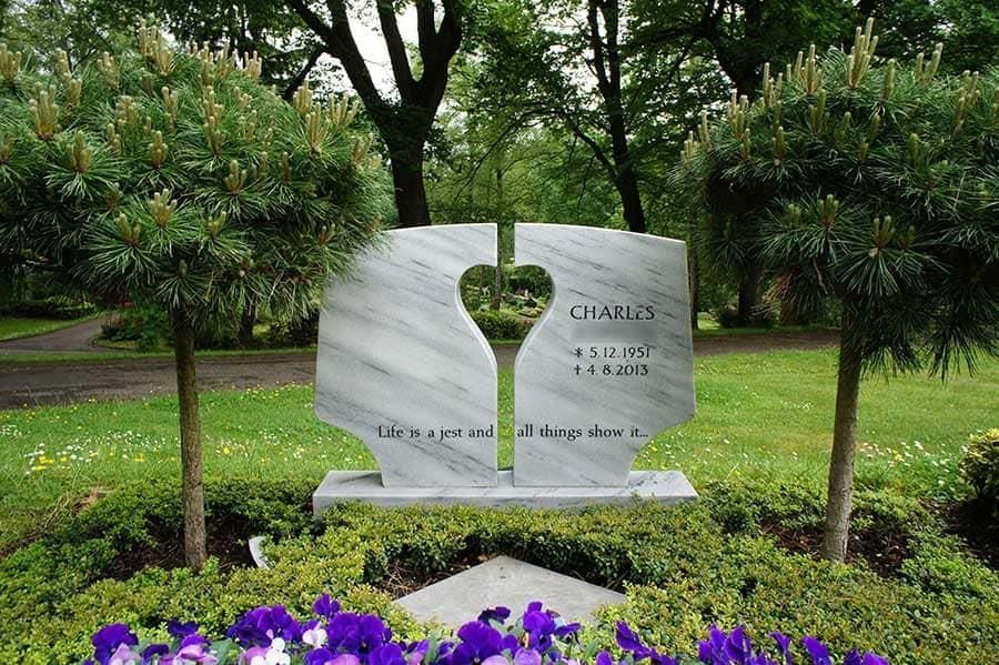 Ein Denkmal für Charles ist von Bäumen und lila Blumen umgeben