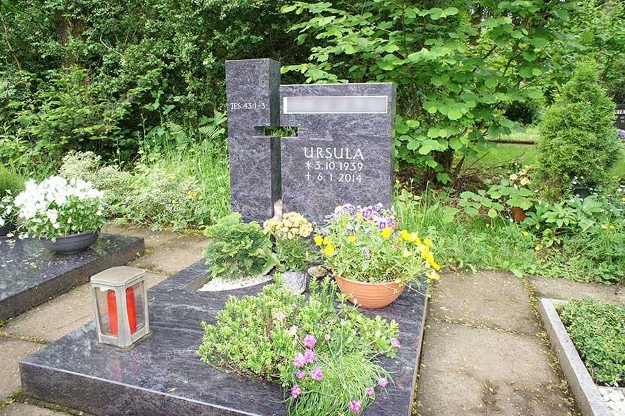 Ein Grab auf einem Friedhof mit Blumen und einem Kreuz
