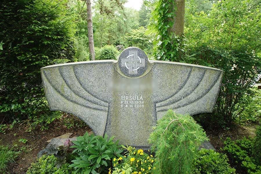 Auf einem Grabstein auf einem Friedhof steht ein Kreuz