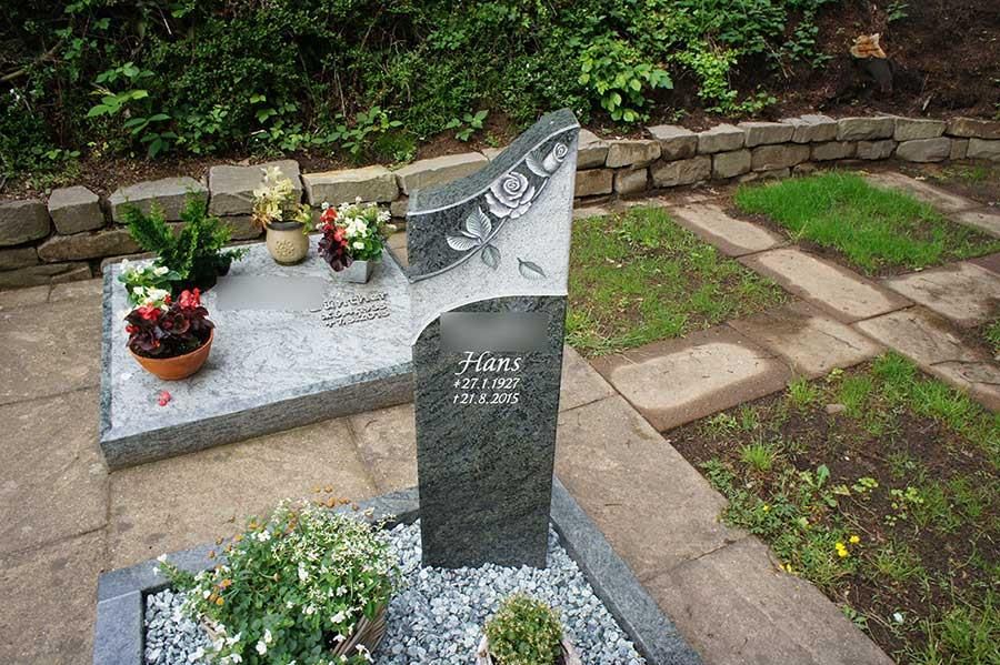 Ein Grab mit Blumen und einem Grabstein mit der Aufschrift „Thomas“