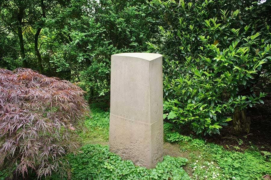 Ein Betonblock inmitten eines Gartens mit Bäumen im Hintergrund