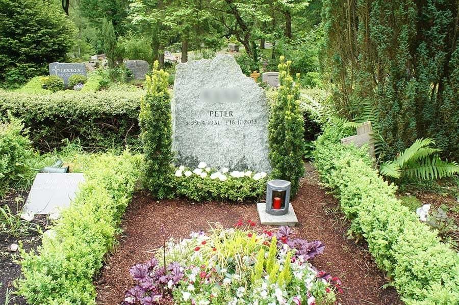 Ein Grab auf einem Friedhof mit Blumen und einer Laterne