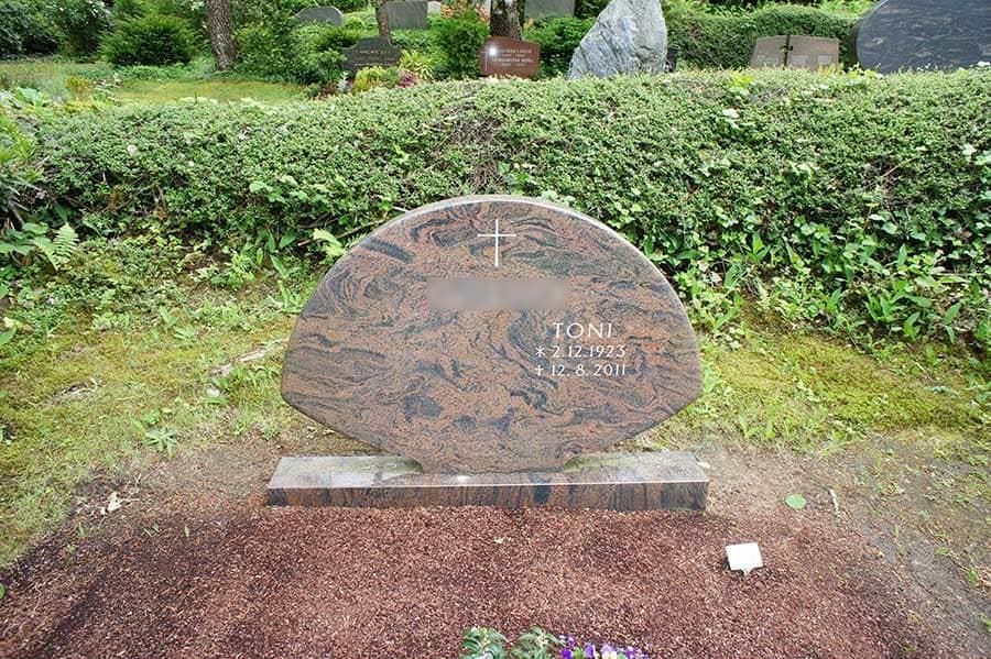 Ein Grabstein mit einem Kreuz darauf auf einem Friedhof.
