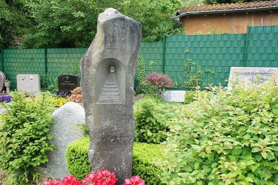 Ein Friedhof mit einem grünen Zaun und einer Statue in der Mitte.