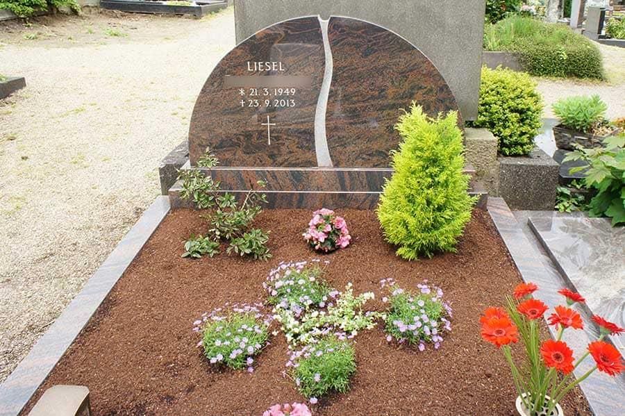 Ein Grab auf einem Friedhof mit Blumen und Pflanzen