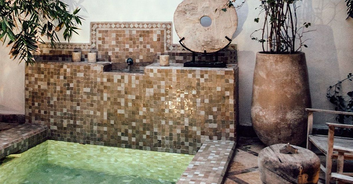  A serene spa setting in Egypt, featuring a small pool surrounded by intricate tilework, a water fountain, and lush greenery