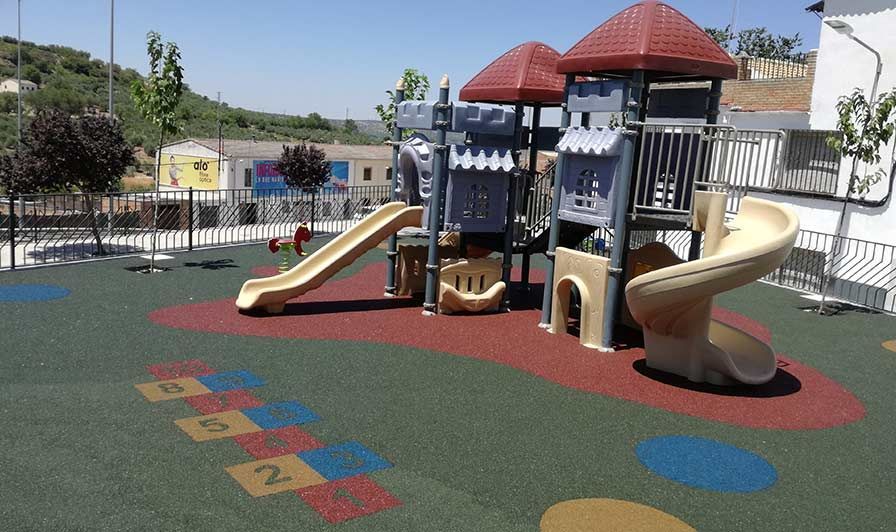 Un parque infantil con tobogán y zona de rayuela.