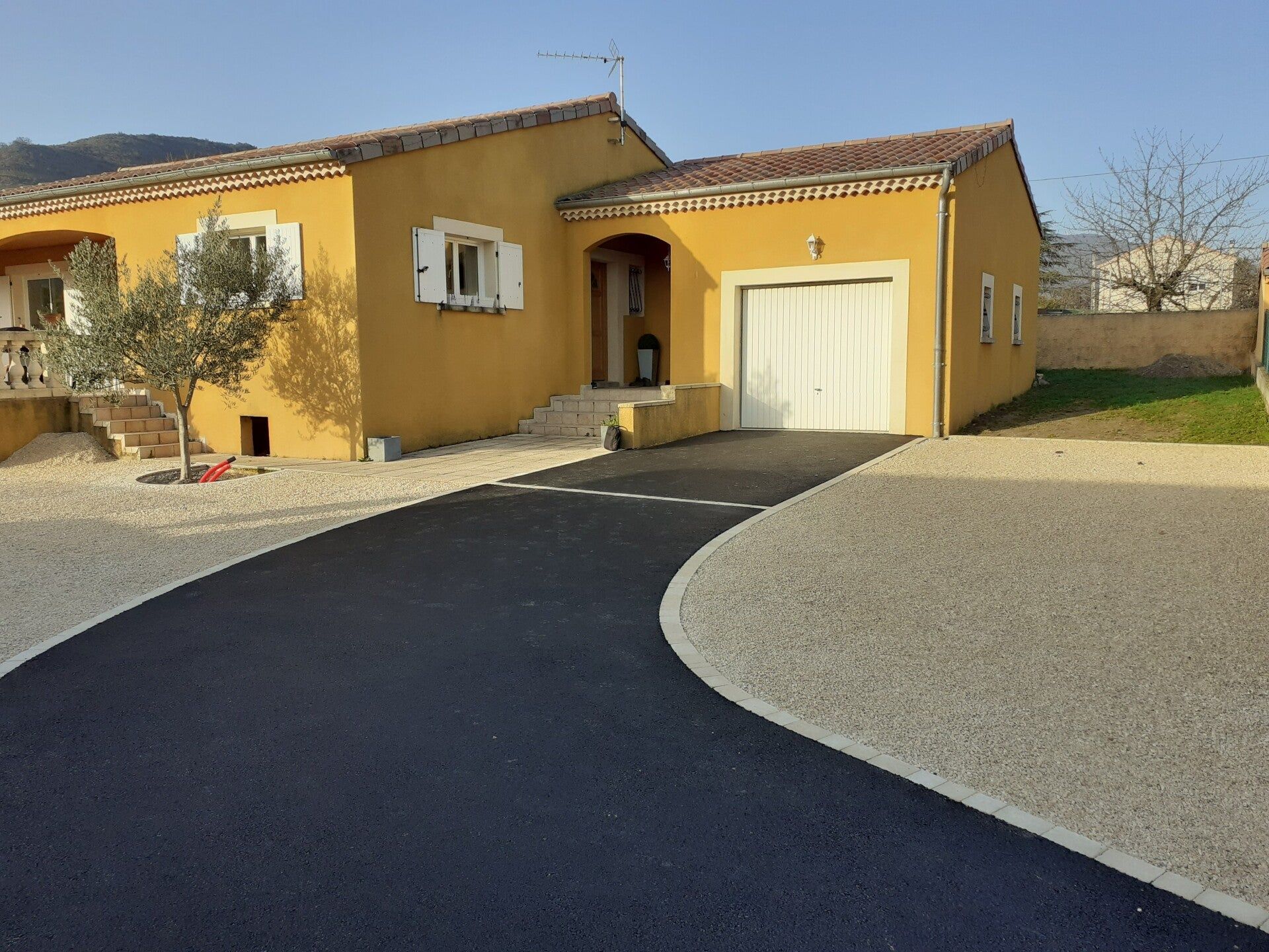 Différents revêtements posés au sol devant une maison aux murs jaune safran sur un soleil couchant de fin d'été 