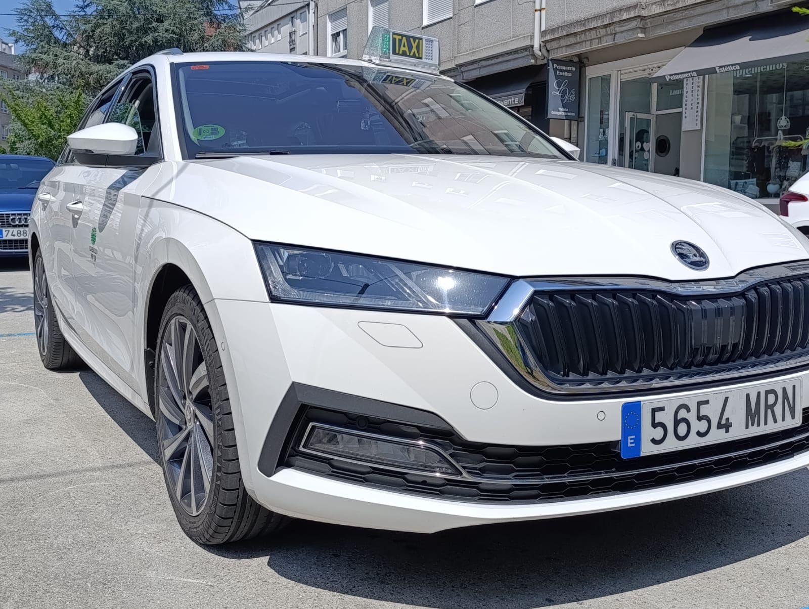 Un Skoda Octavia blanco está estacionado frente a un edificio.