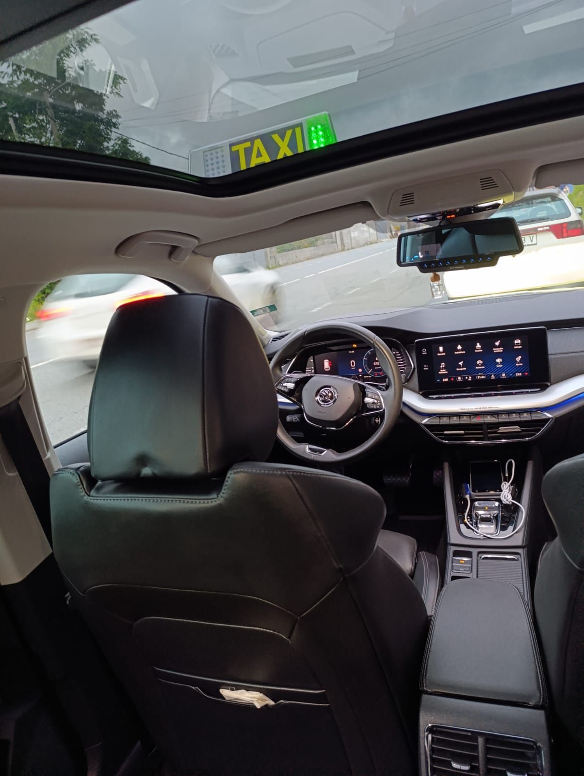 El interior de un automóvil con techo corredizo y un cartel de taxi en el parabrisas.