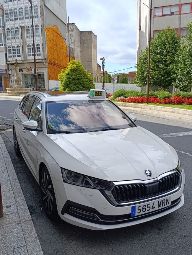 Un taxi blanco está estacionado al costado de la carretera.