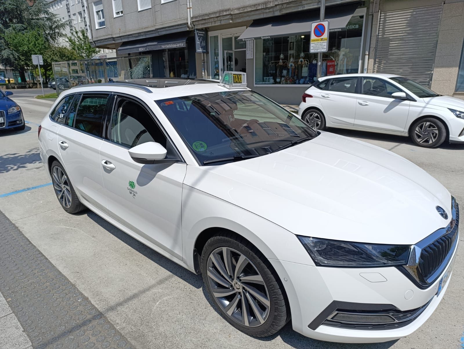 Un coche blanco está aparcado al costado de la carretera frente a un edificio.