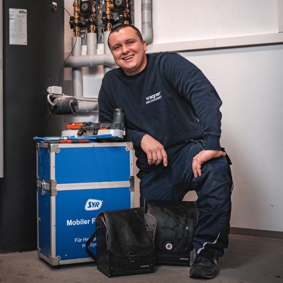 Günter Wagner GmbH – Techniker posiert mit Werkzeugkasten vor Rohrleitungen