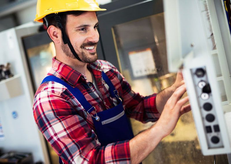 Un hombre que lleva un casco está trabajando en una máquina en una fábrica.
