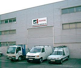 Tres furgonetas blancas están estacionadas frente a un gran edificio.