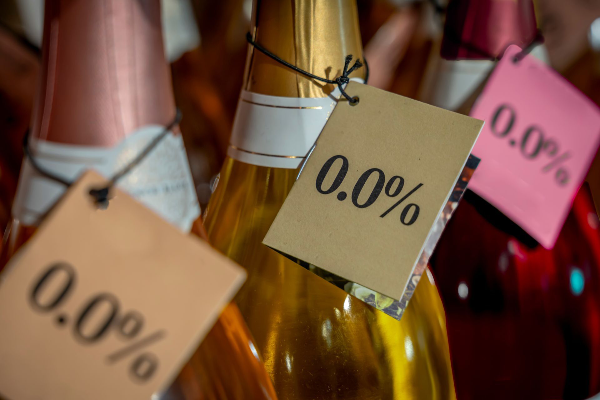 Des bouteilles en verre avec des étiquettes « 0,0 % » suspendues, suggérant des boissons sans alcool