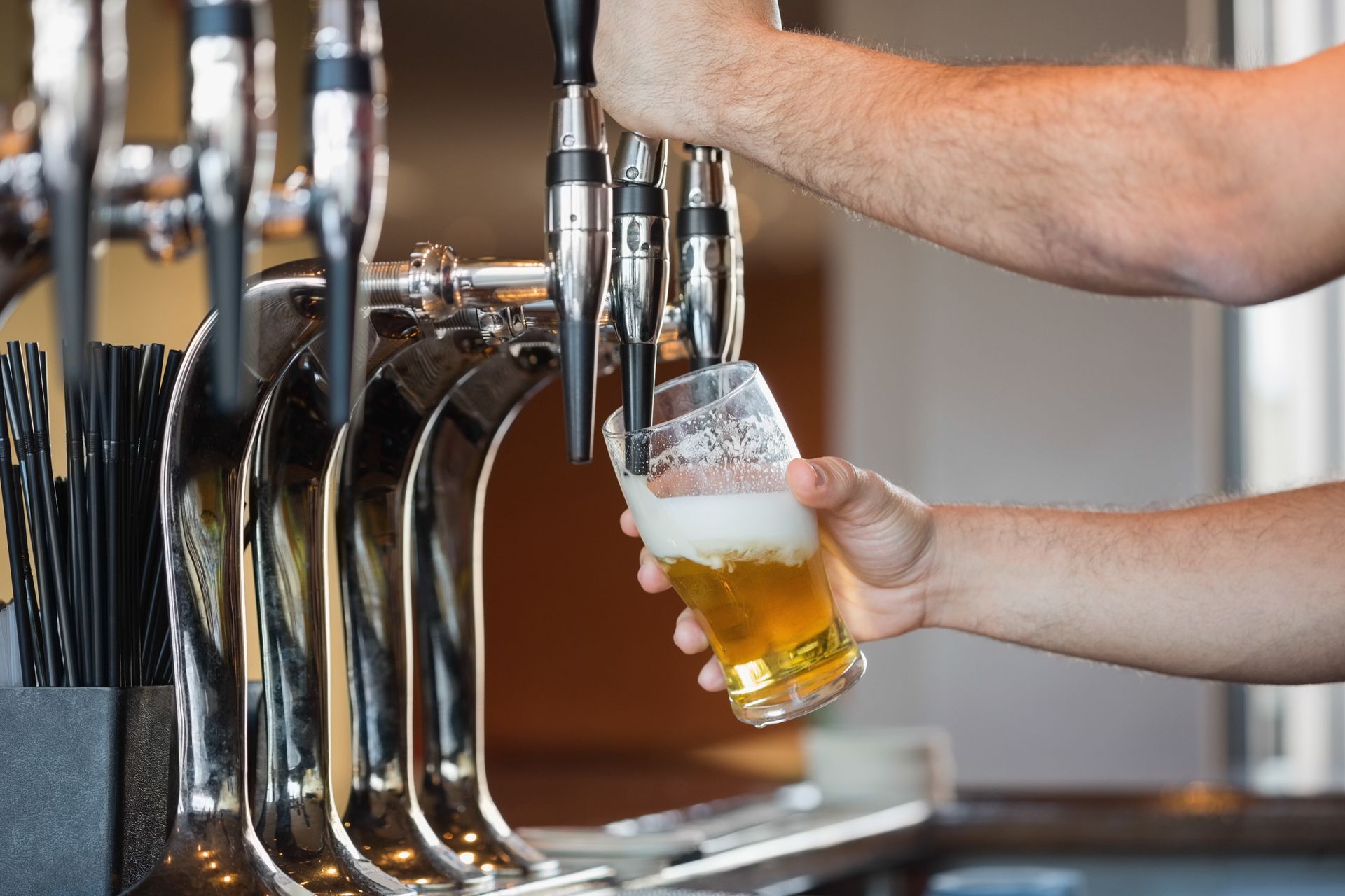 Une main sert un verre de bière à la tireuse dans un bar