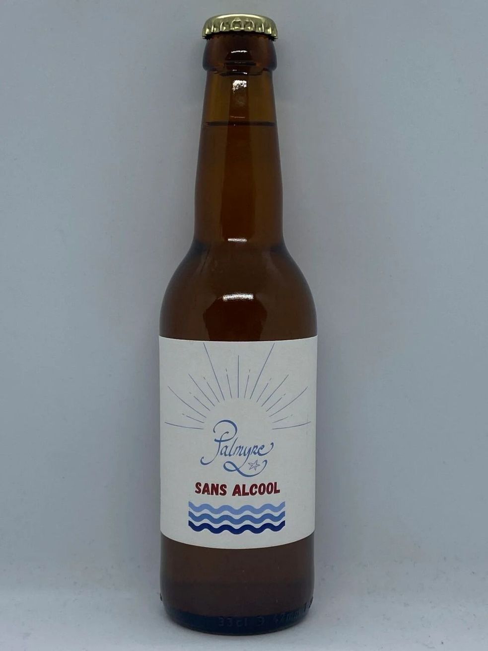 Bouteille de bière en verre brun avec une étiquette blanche et un bouchon doré sur un fond uni