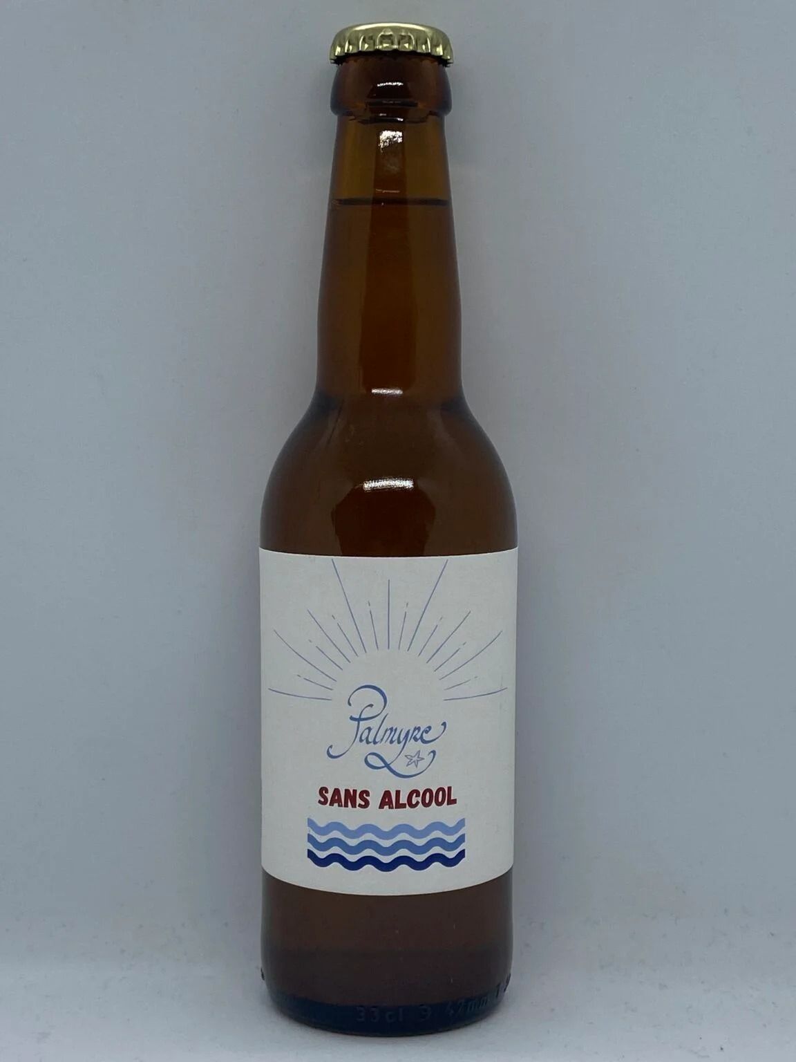 Bouteille de bière en verre brun avec une étiquette blanche et un bouchon doré sur un fond uni