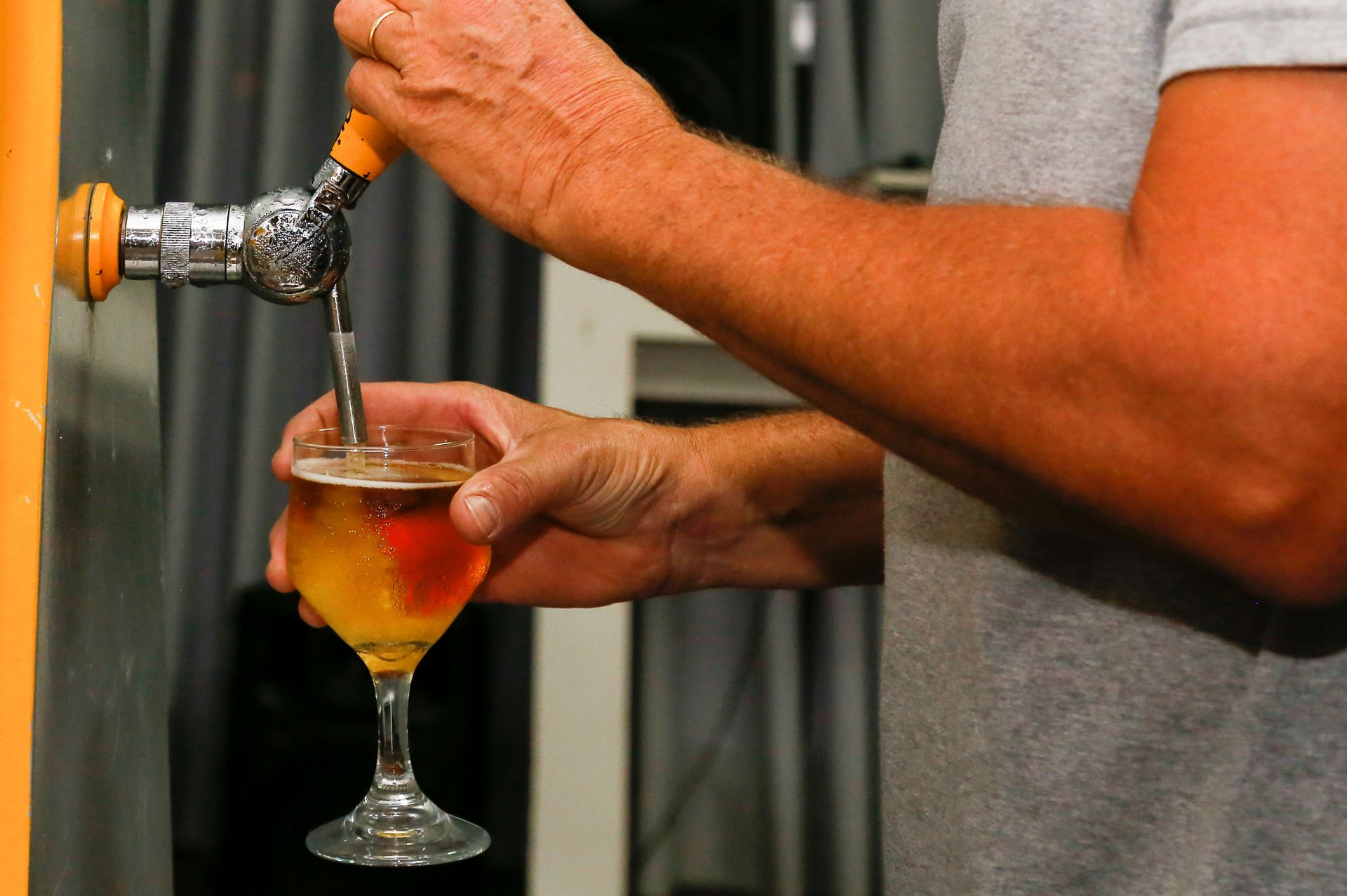 Une personne sert de la bière à la pression dans un verre à pied.