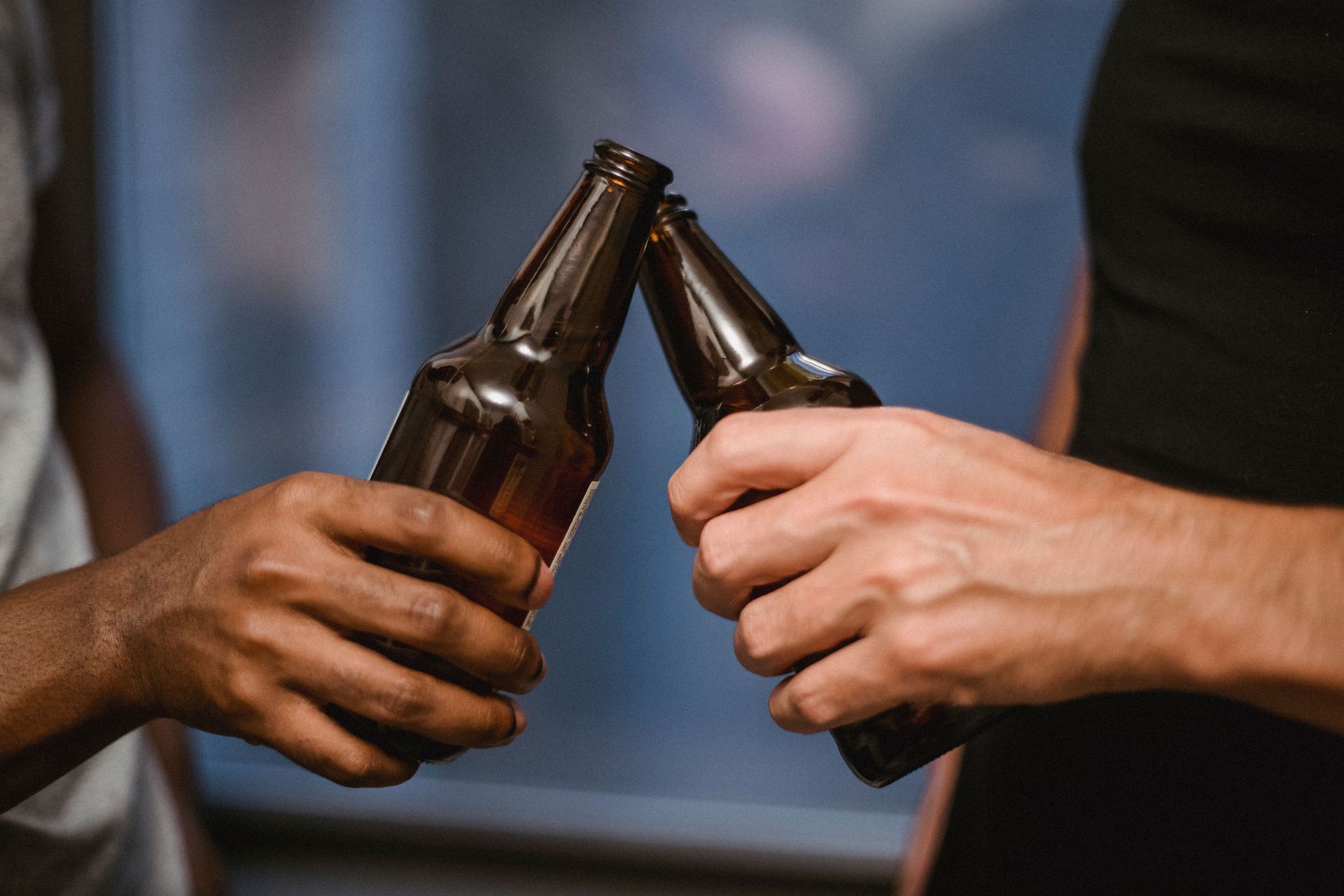 Deux personnes trinquent avec des bouteilles de bière brune