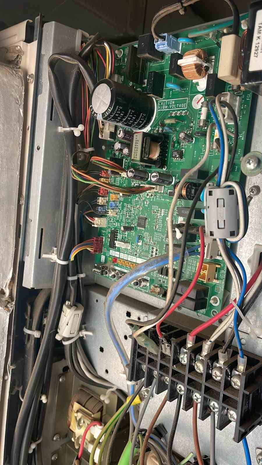 Primer plano del interior de un dispositivo electrónico abierto, con placa de circuito impreso verde, cables y conectores.