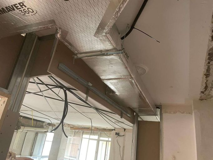 Conductos de ventilación y cables colgantes a la vista en una habitación en obras.