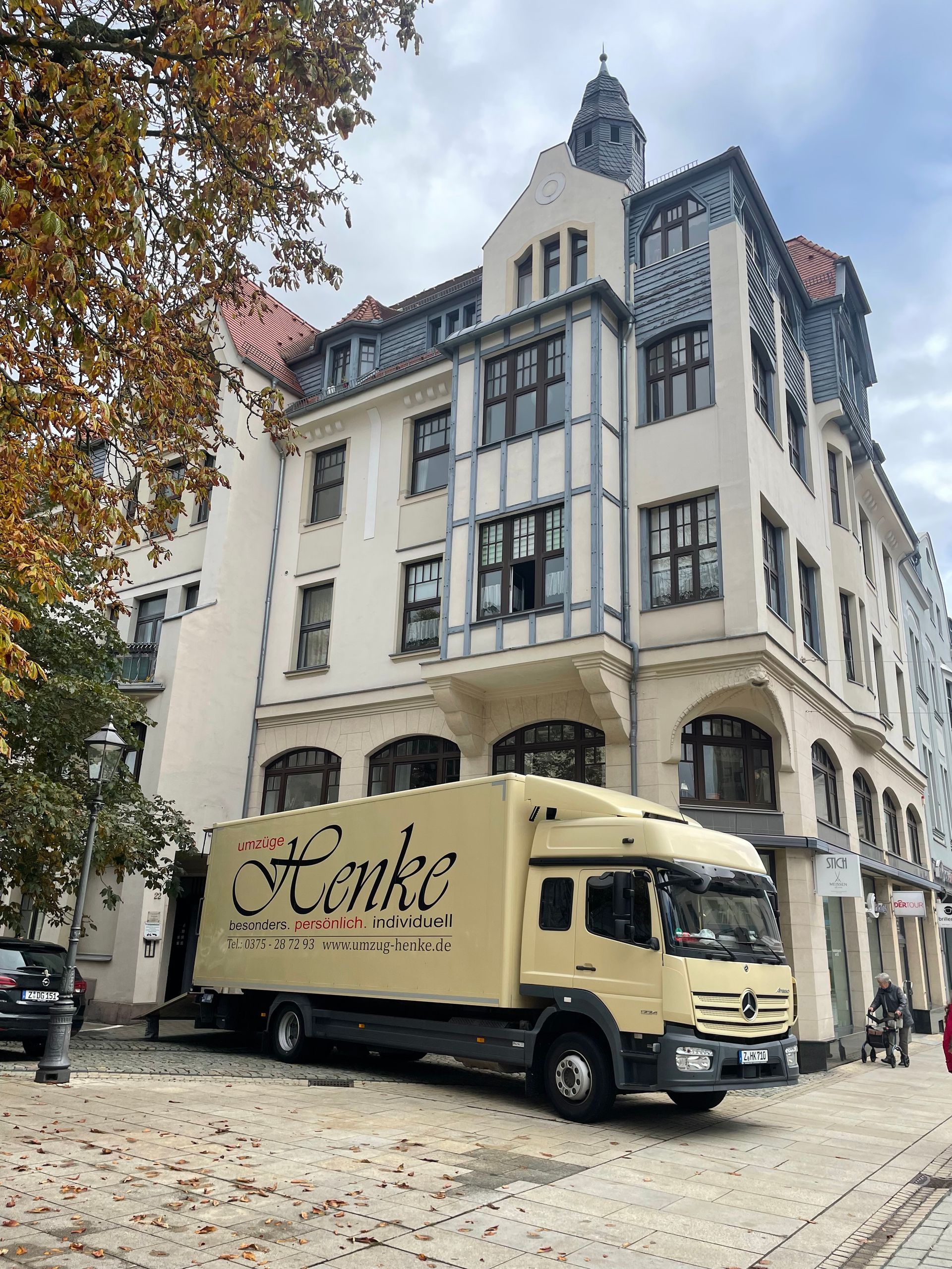 Historisches Mehrfamilienhaus mit Stuckfassade und Erker. Umzugswagen von Umzüge Henke davor. 