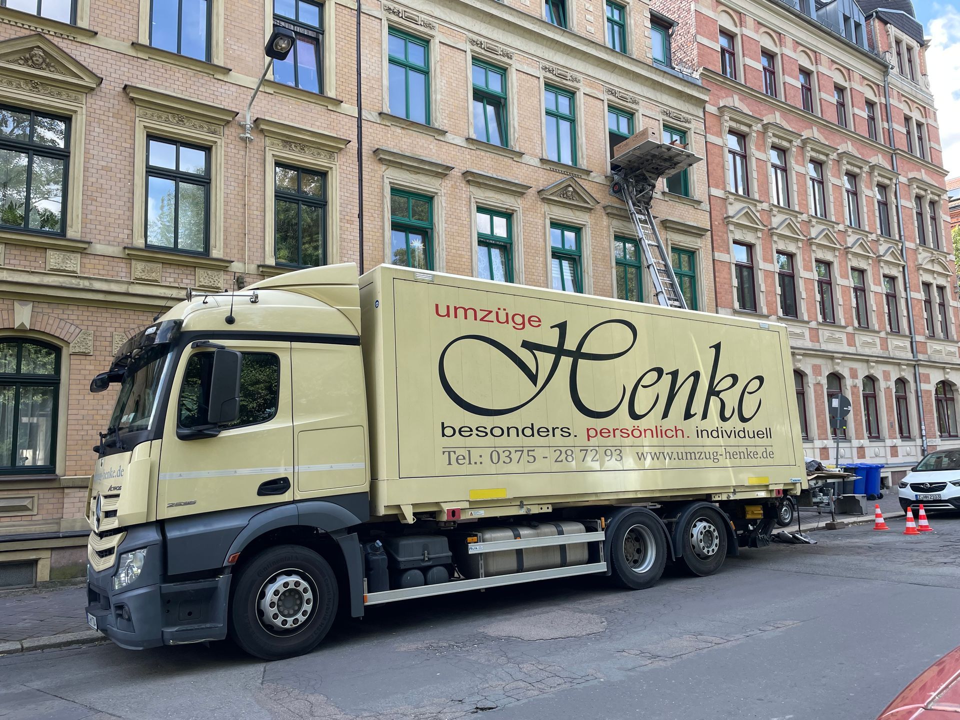 Umzugs-LKW in einer Stadtstraße vor Wohnhäusern.