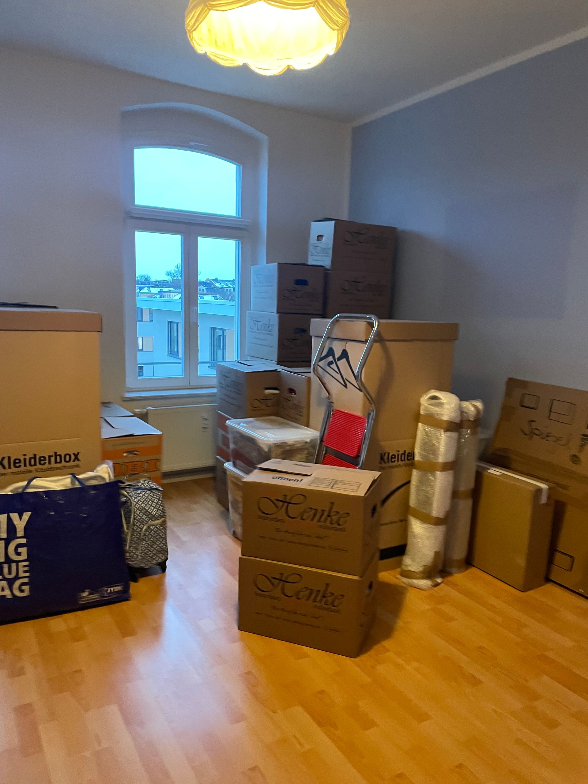 Wohnraum mit Umzugskartons nahe einem Fenster.