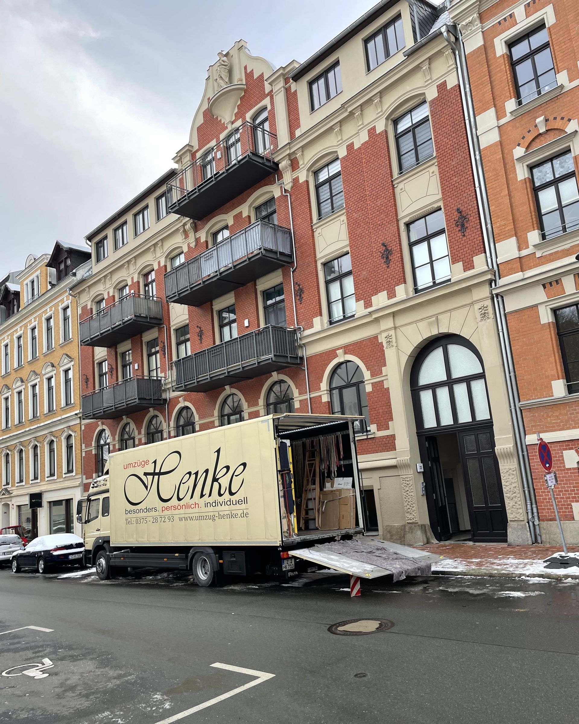 Umzug mit Möbellift an einem Wohnhaus, Möbel werden über den Balkon transportiert.