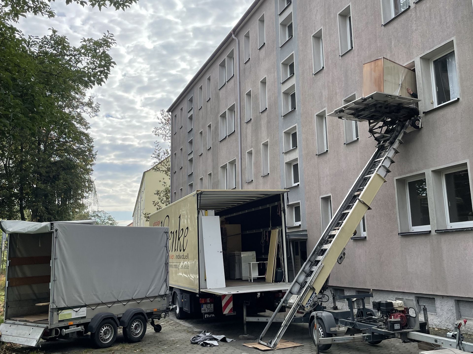 Umzug mit Möbellift an einem Wohnhaus, Möbel werden über den Balkon transportiert.