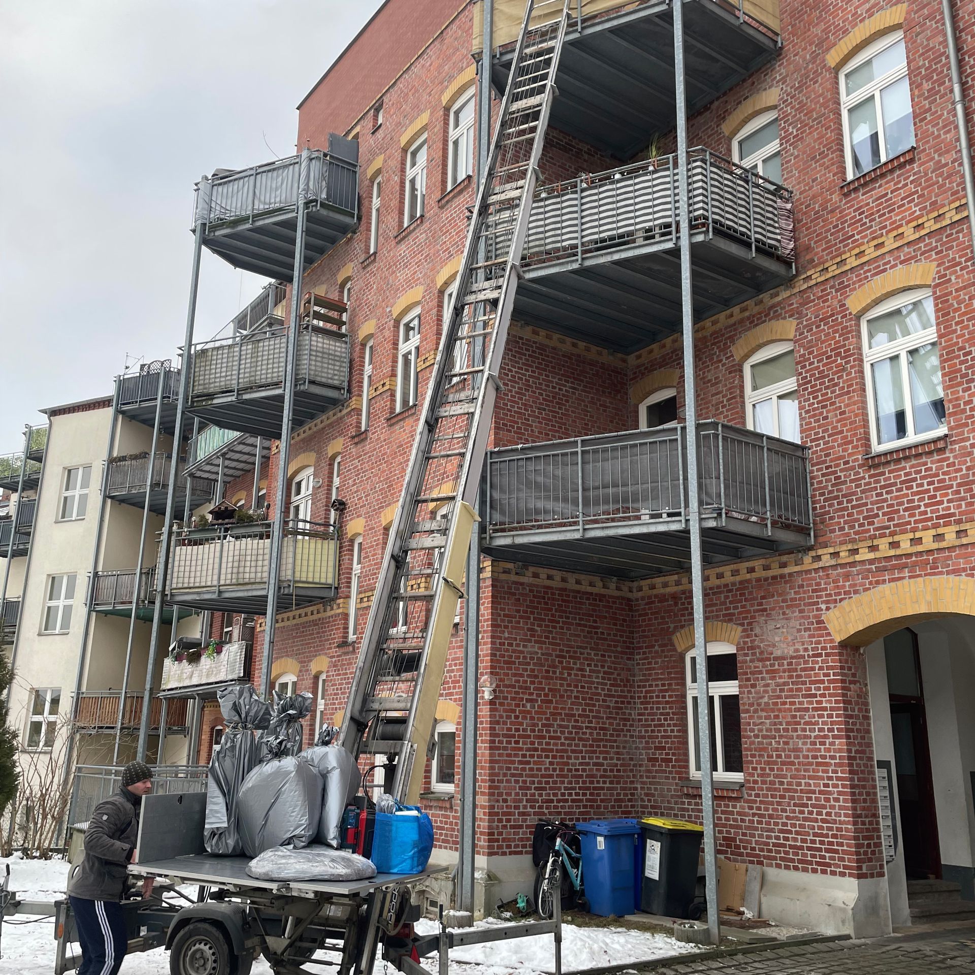 Umzugs-LKW steht vor einem Mehrfamilienhaus, Ladefläche geöffnet.