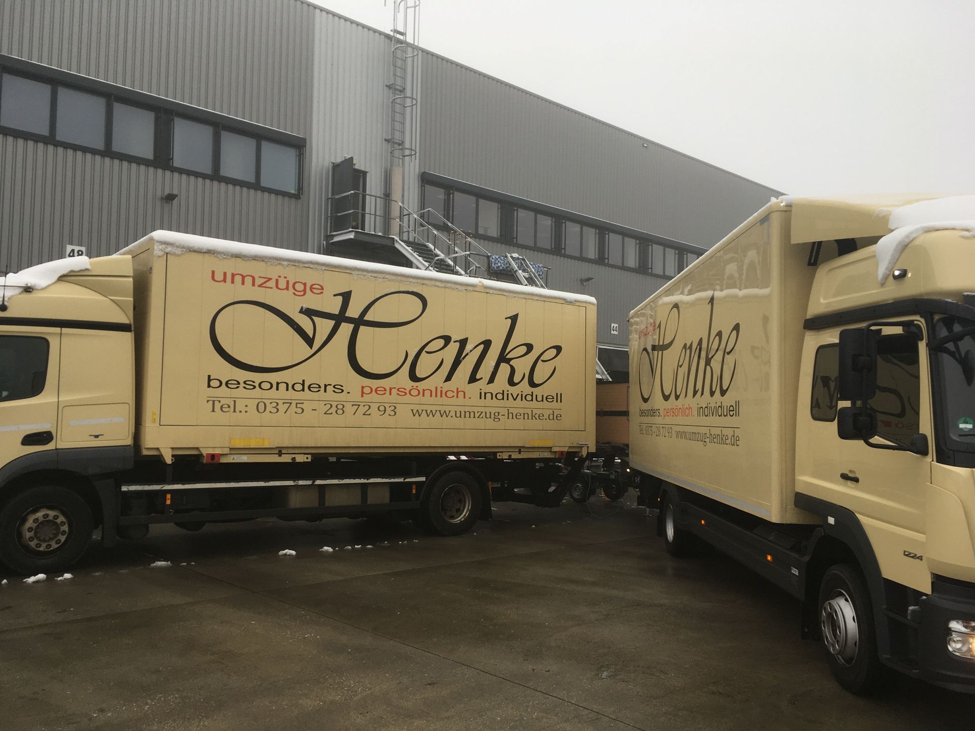 Zwei geparkte Umzugs-LKW auf einem Firmengelände.