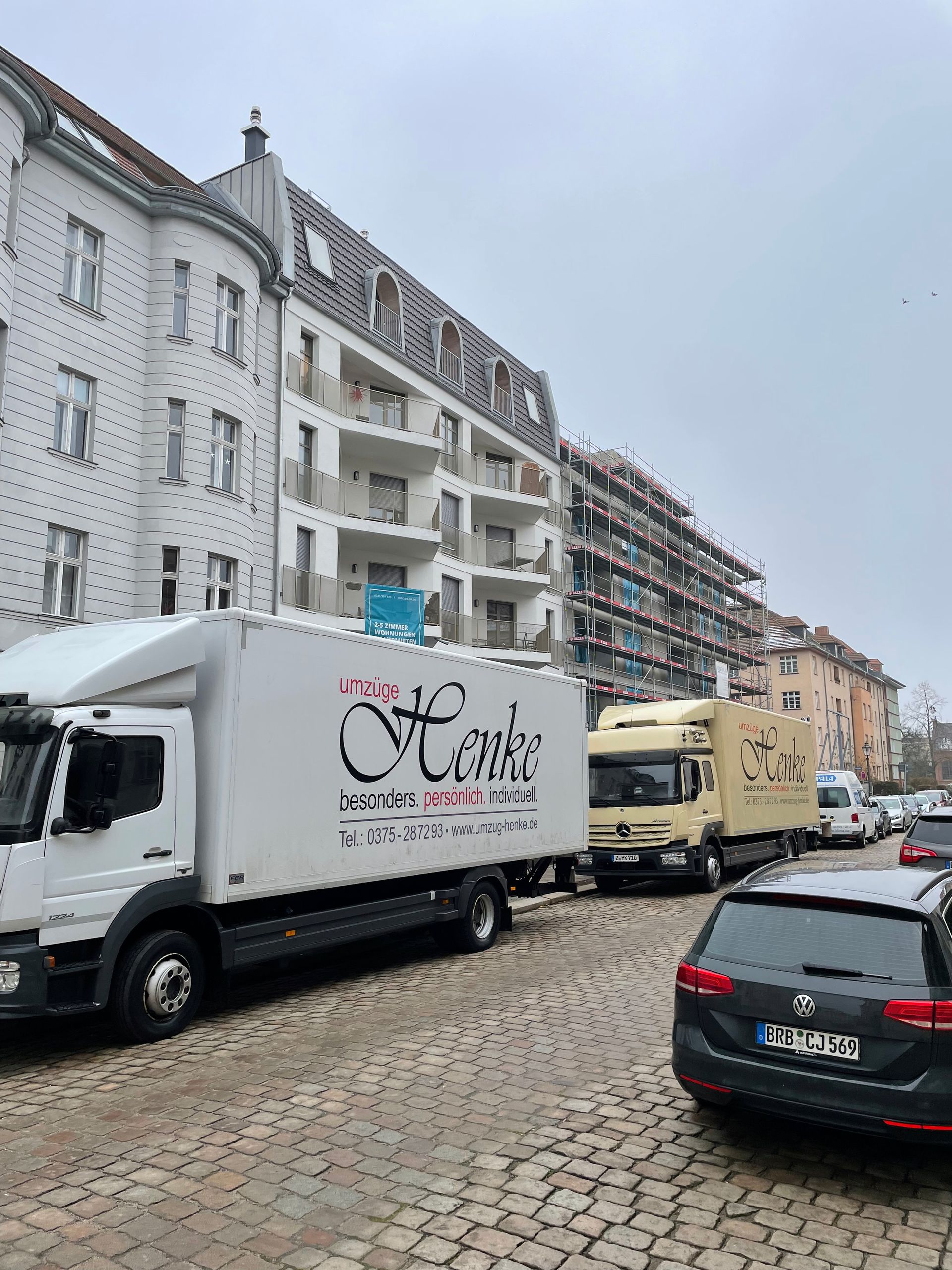 Mehrere Umzugs-LKW stehen in einer Wohnstraße.