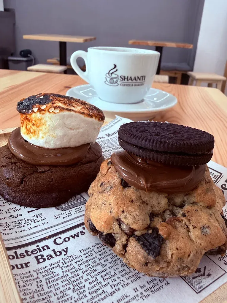 En una mesa de una cafetería, se pueden ver varios postres y una taza de café