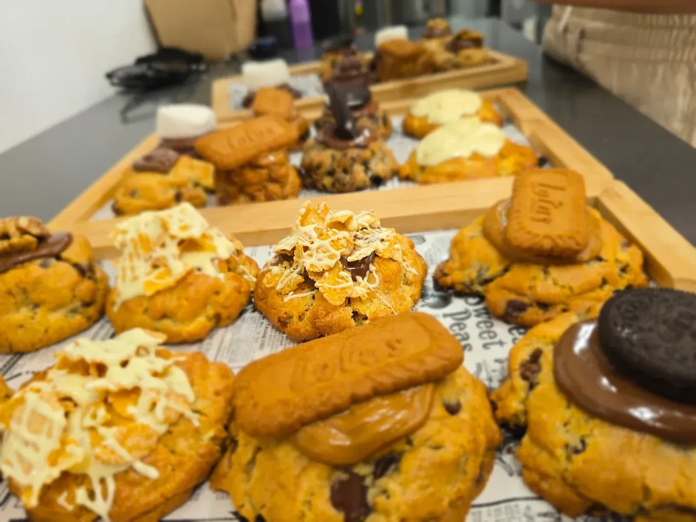 Galletas y pasteles variados dispuestos en una bandeja de madera, con coberturas de chocolate y crema.