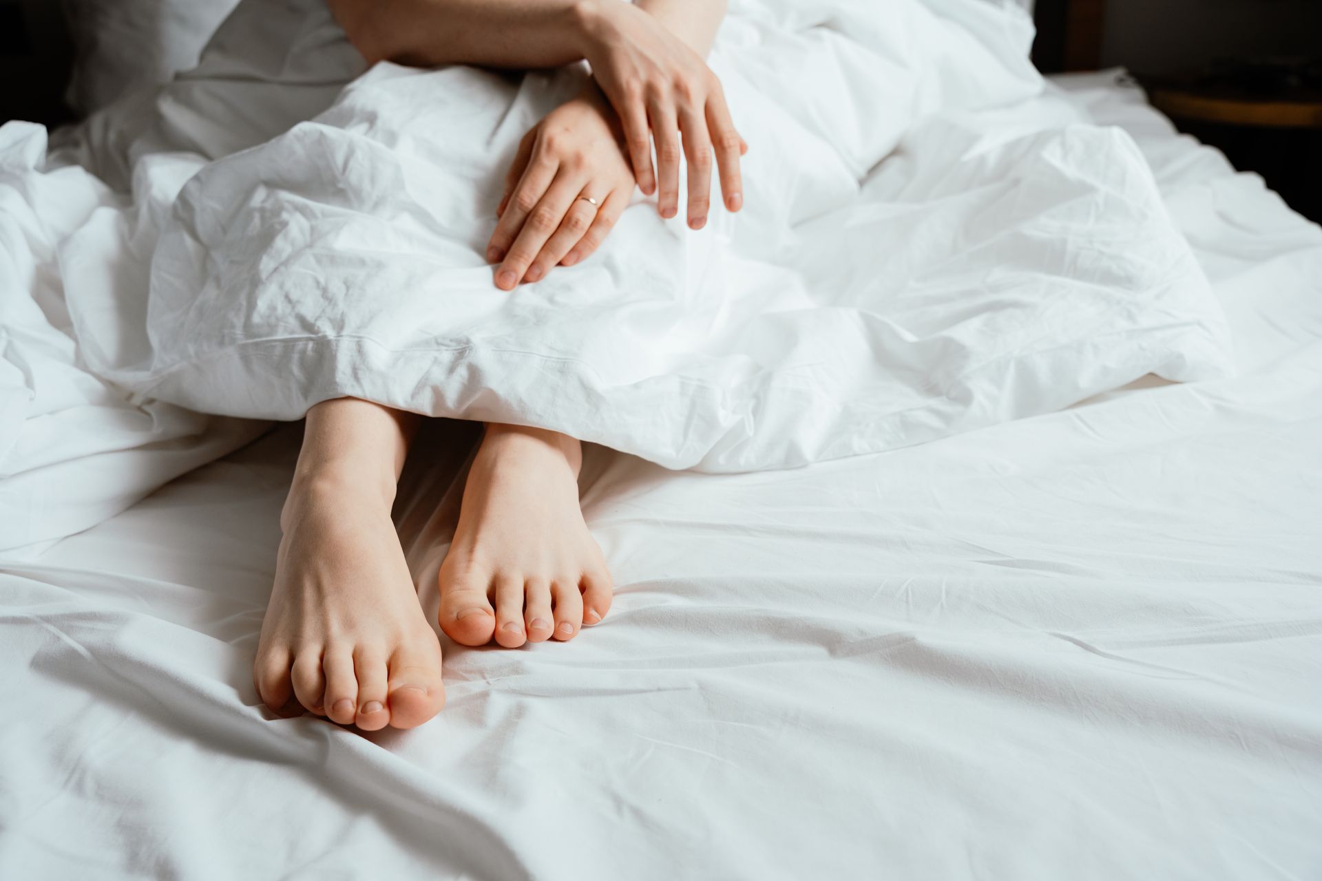 Pieds et mains nus sur des draps blancs.