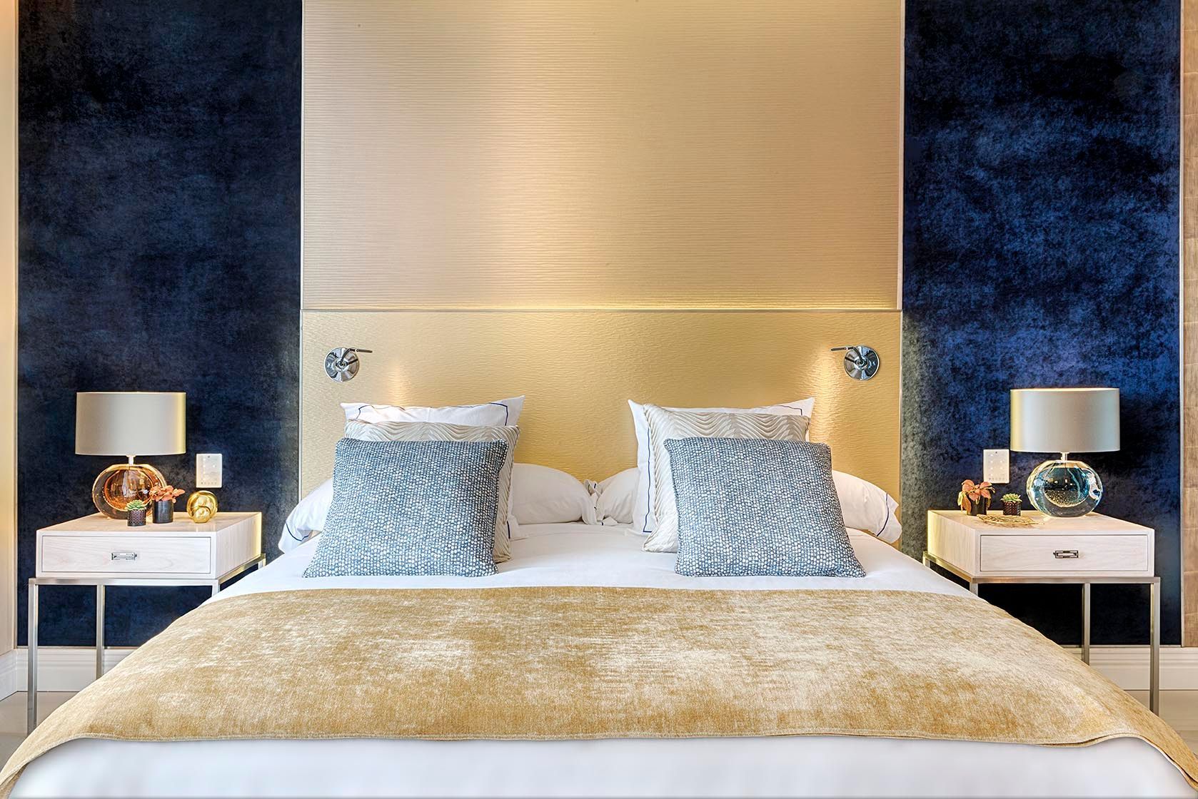 Un dormitorio con una cama, mesitas de noche y lámparas.
