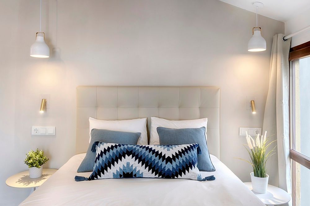 Un dormitorio con una cama, almohadas, lámparas y una ventana.