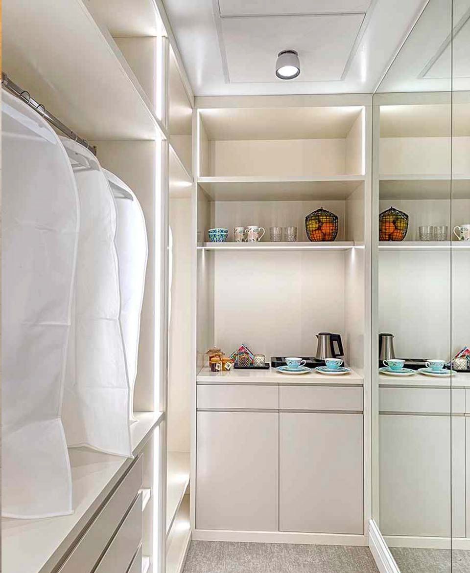 Un vestidor con muchos estantes y un espejo.