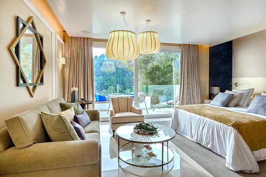 Una habitación de hotel con una cama tamaño king, sofá, mesa de café y sillas.