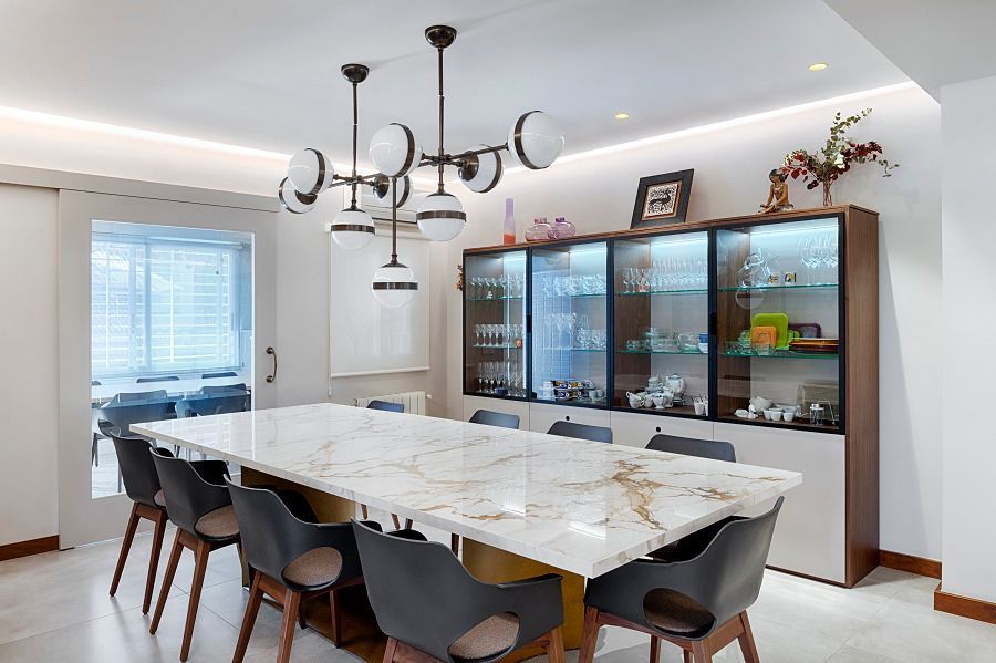Un comedor con una larga mesa de mármol y sillas.