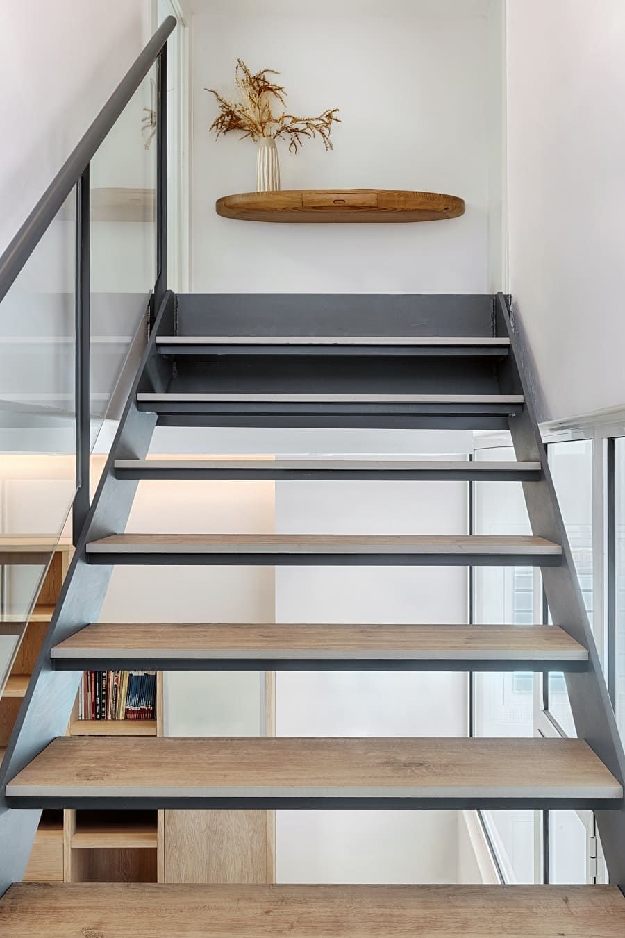 Una escalera con escalones de madera y barandilla de cristal en una casa.