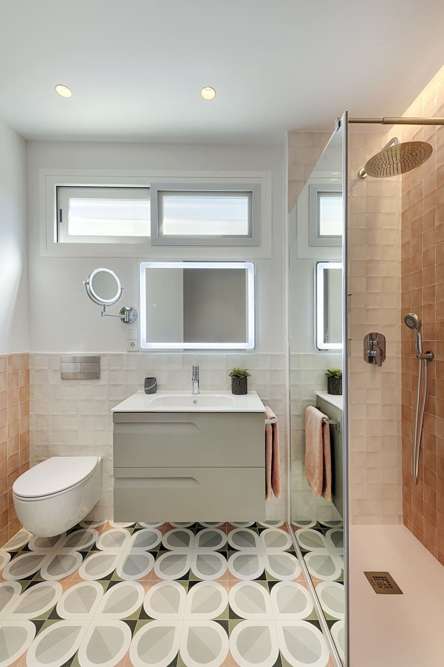 Un baño con inodoro, lavabo, espejo y ducha.