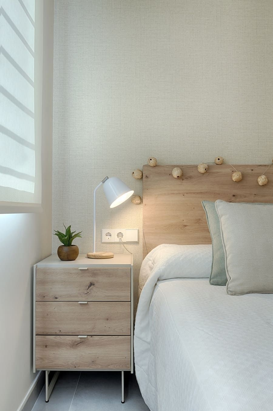 Un dormitorio con cama, mesita de noche y lámpara.