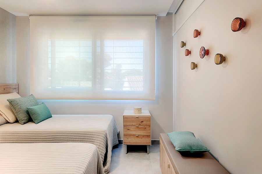 Un dormitorio con dos camas, una mesita de noche y una ventana.