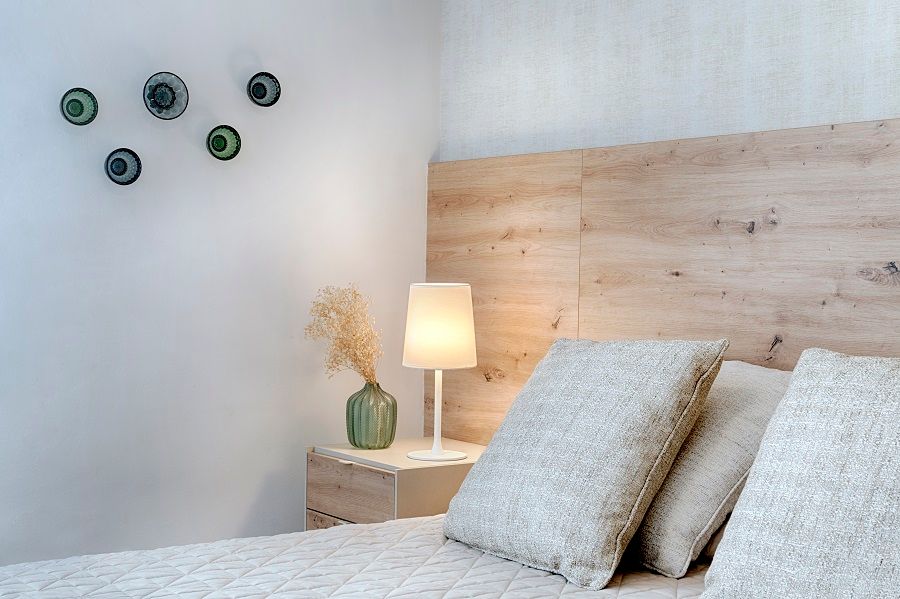 Un dormitorio con una cama, mesita de noche y lámpara.