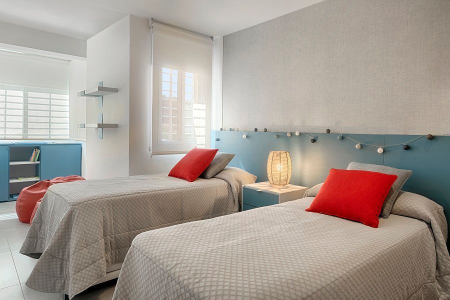 Un dormitorio con dos camas individuales y un cabecero azul.