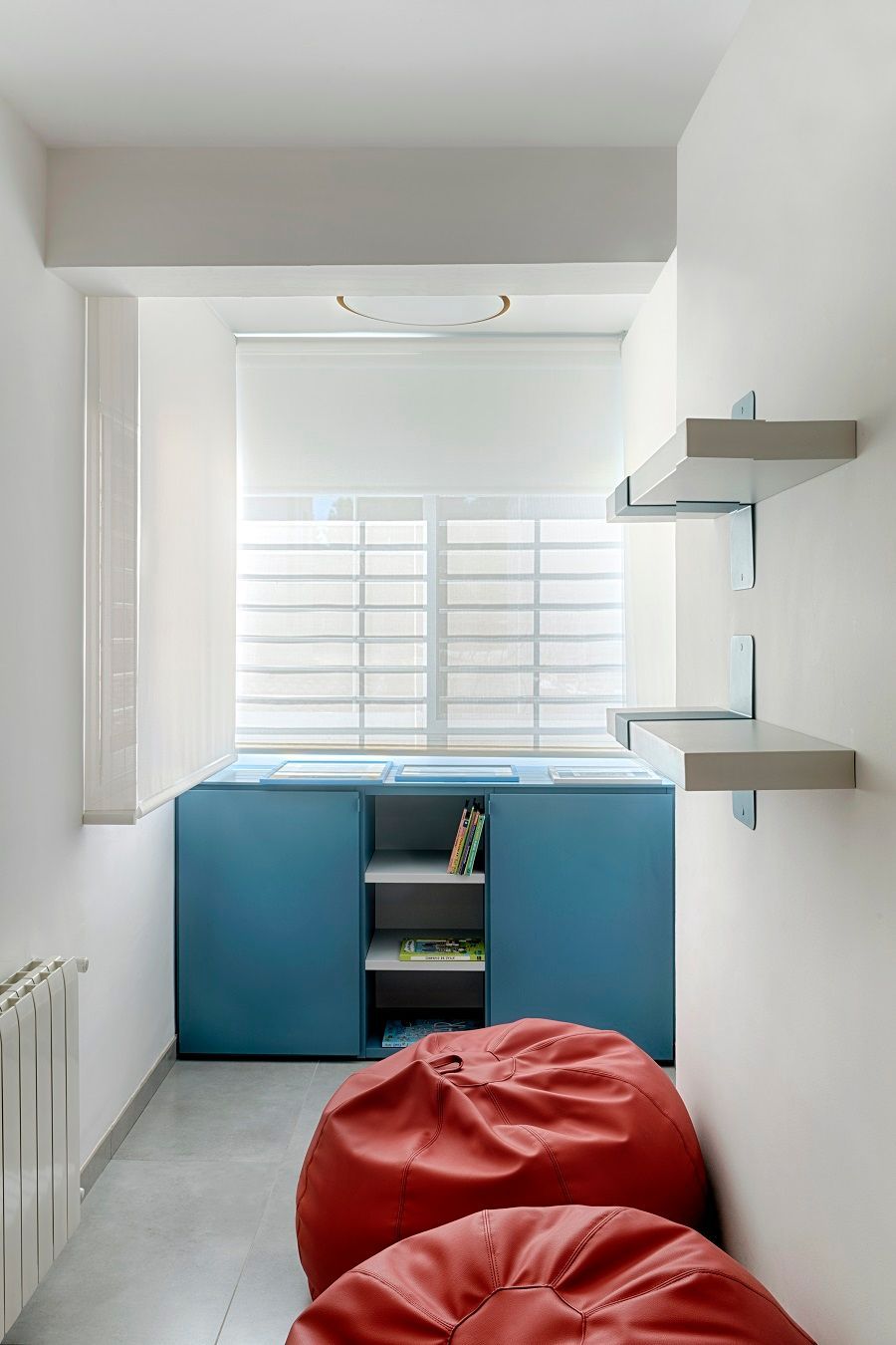 Una habitación con dos sillones puff rojos y una ventana.